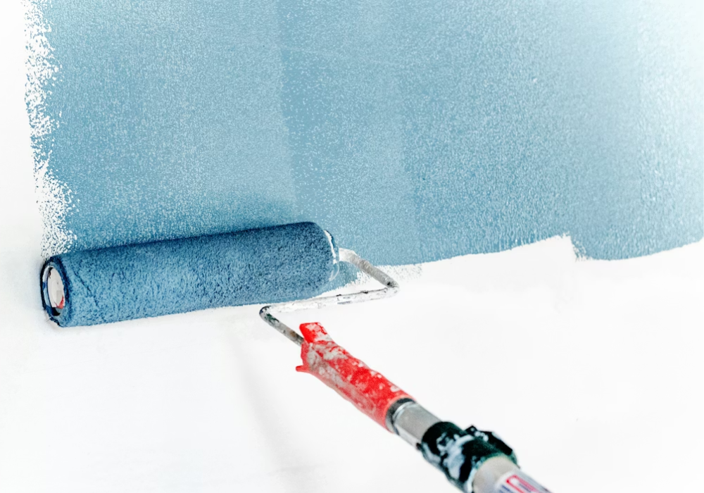 A white wall being painted with a roller, and light blue paint
