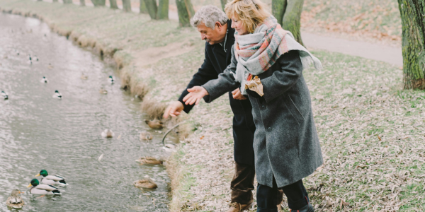 A couple feeding ducks on a snowy day